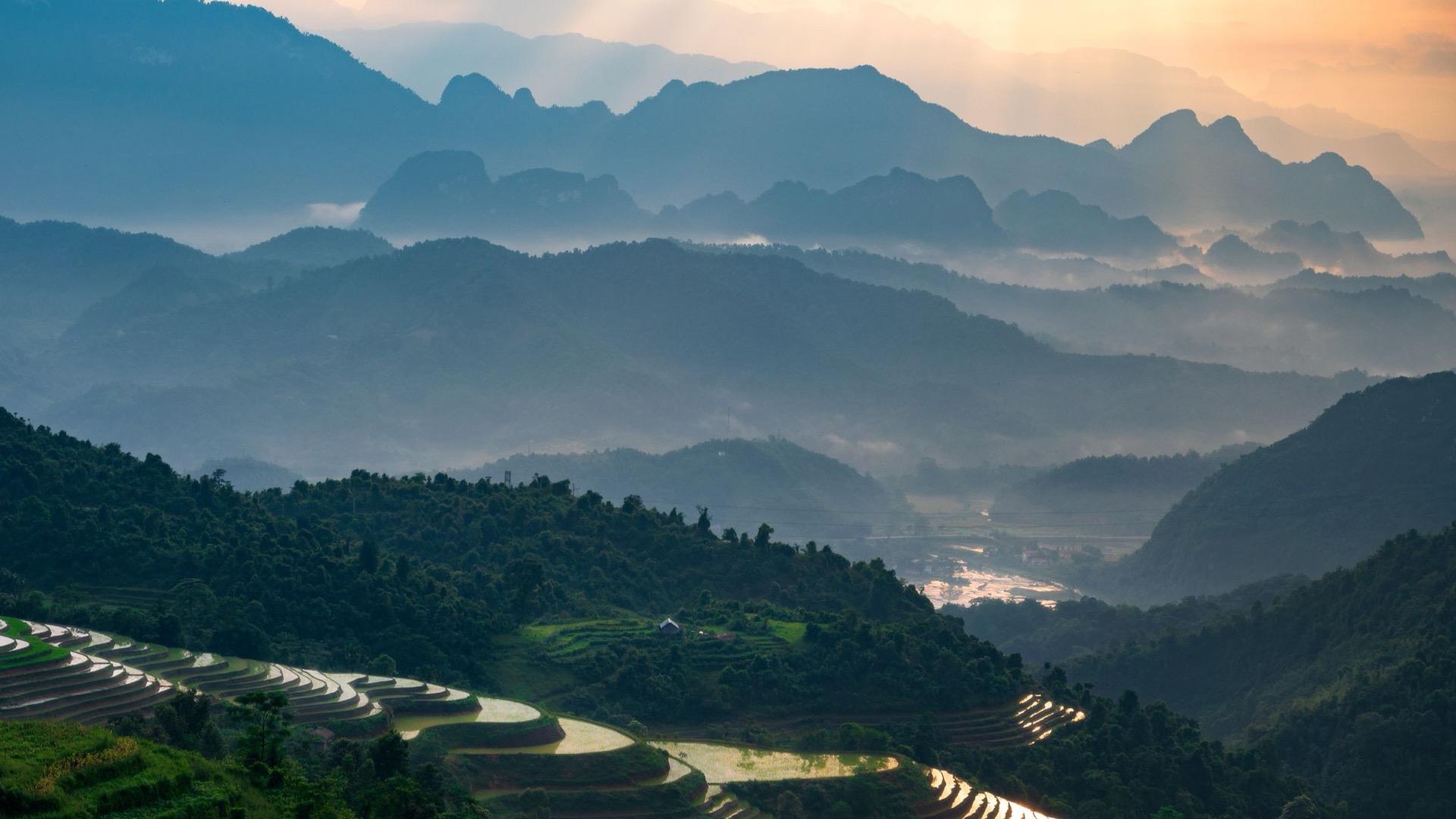 Terraced fields at dawn, ridges fading into the haze behind them.