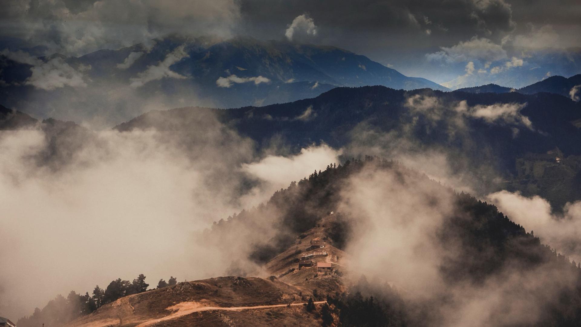 Dark mountain ridges under low cloud, one slope caught in the light.