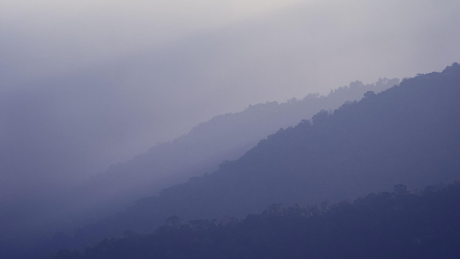 Layered mountain ridges receding into fog, each fainter than the last.